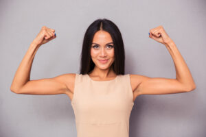 Woman holding up both arms to show slim, toned biceps after arm lift surgery in San Diego