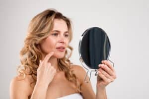 Woman looking in the mirror to see if a facelift is right for her in La Jolla, CA
