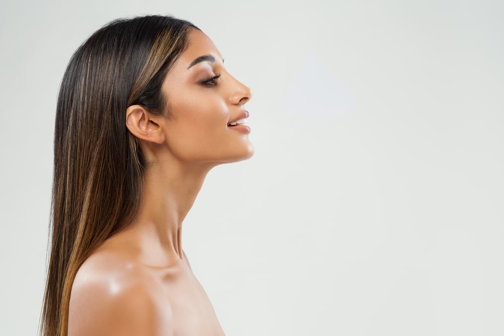 Side profile of woman's breasts as she olds breast implants in La Jolla, CA Side profile of a woman after rhinoplasty in La Jolla, CA